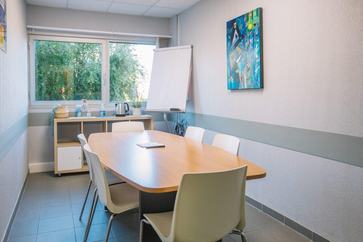 Salle de réunion du centre Espace Entreprise Millénaire, table ovale, paperboard et fenêtre